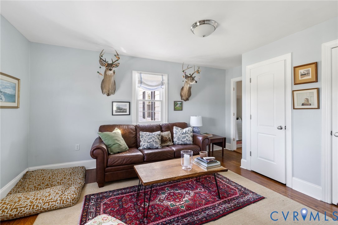 Hardwood flooring, light blue wall paint, white trim, recessed window, and a flush mount light fixture