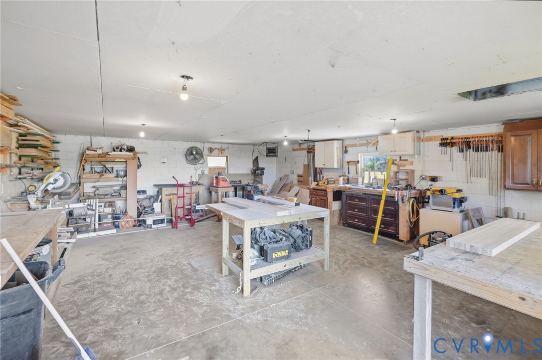 Spacious workshop featuring a concrete floor, built-in cabinetry, and multiple workbenches