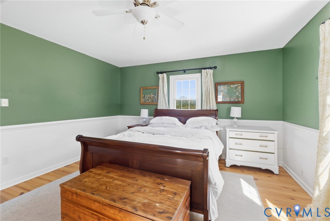 Hardwood flooring, painted wainscoting, and a ceiling fan with integrated lighting