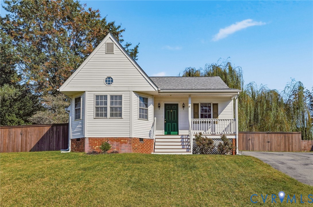 White siding exterior with a dark green entry door, covered front porch, and a mature weeping willow tree White siding exterior with a dark green entry door, covered front porch, and a mature weeping willow tree