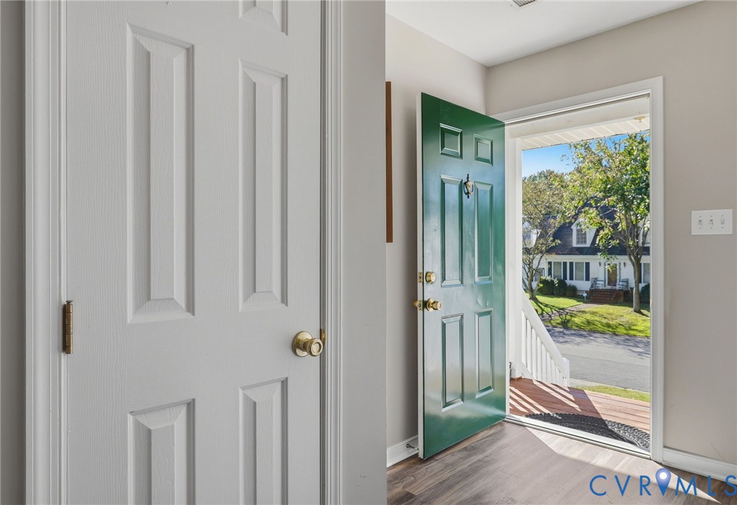 Entryway featuring a paneled green front door, wood-finish flooring, and a white interior door Entryway featuring a paneled green front door, wood-finish flooring, and a white interior door