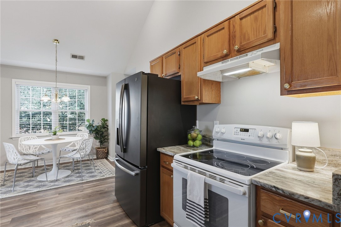 Vaulted ceiling, wood-finish flooring, wood cabinetry, stone countertops, and a full suite of appliances