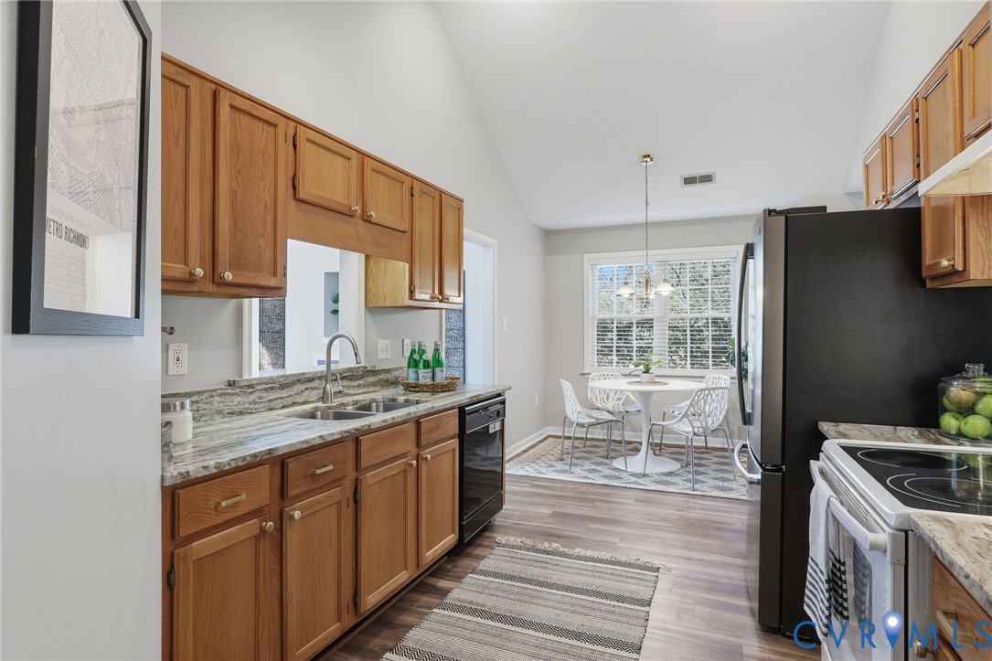 Kitchen featuring light wood cabinetry, stone countertops, double basin sink, and wood-finish flooring Kitchen featuring light wood cabinetry, stone countertops, double basin sink, and wood-finish flooring