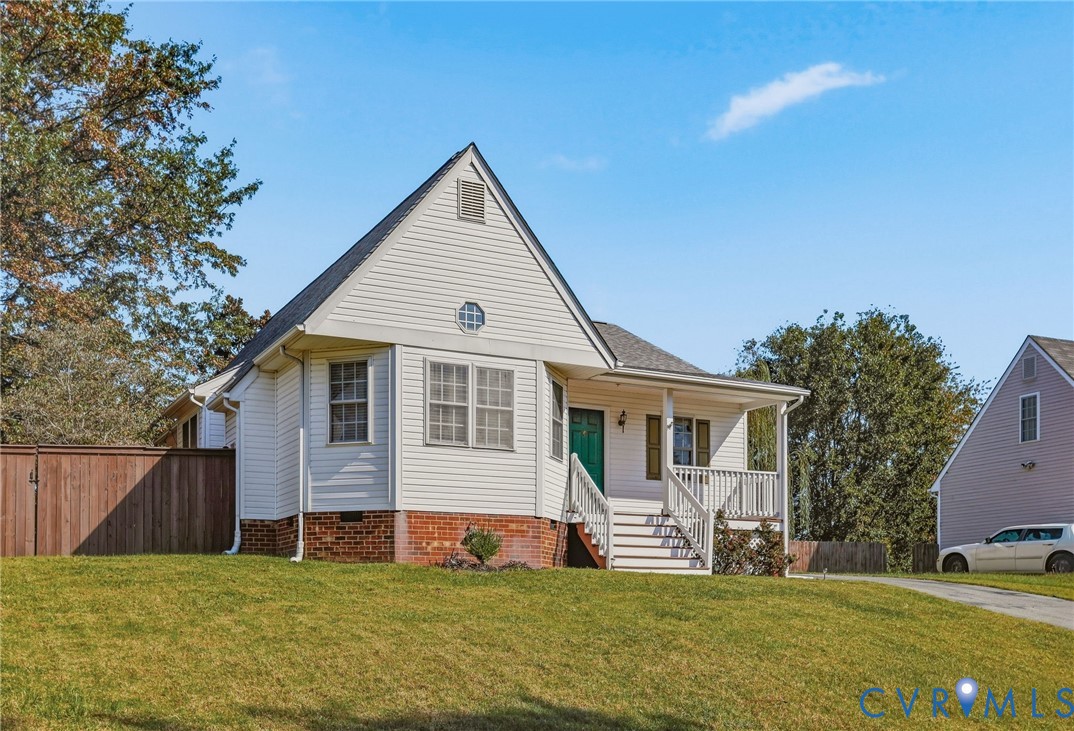 Gable roofline with a round accent window, white siding, covered front porch with white railing, and a sloped lawn Gable roofline with a round accent window, white siding, covered front porch with white railing, and a sloped lawn