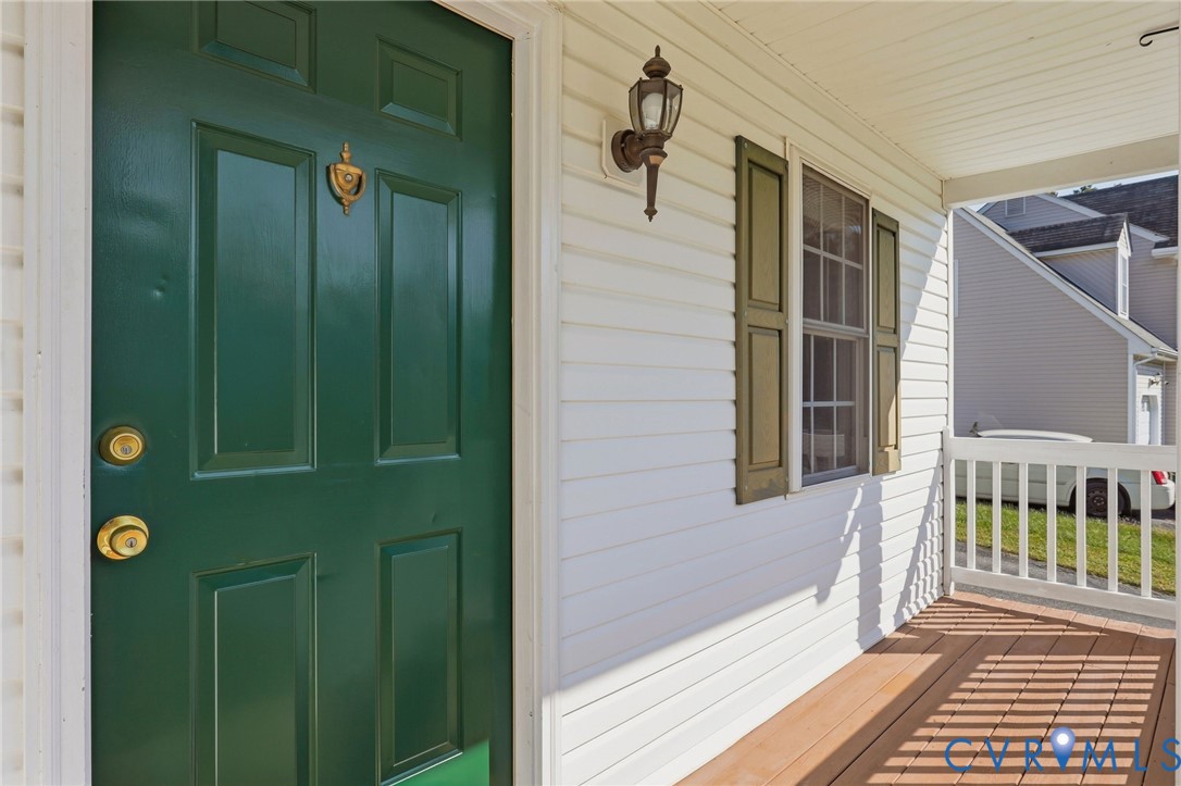 Entry porch featuring a paneled door, decorative door knocker, and wood-finish flooring Entry porch featuring a paneled door, decorative door knocker, and wood-finish flooring
