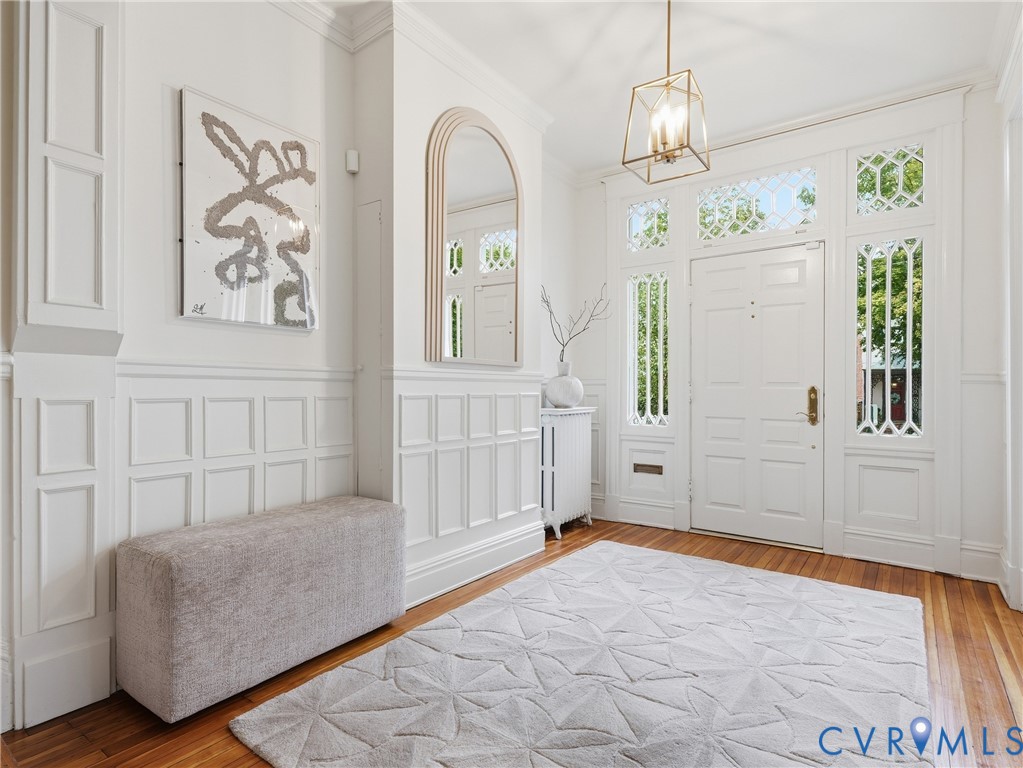 Hardwood flooring, paneled wainscoting, intricate transom windows, and a decorative pendant light fixture