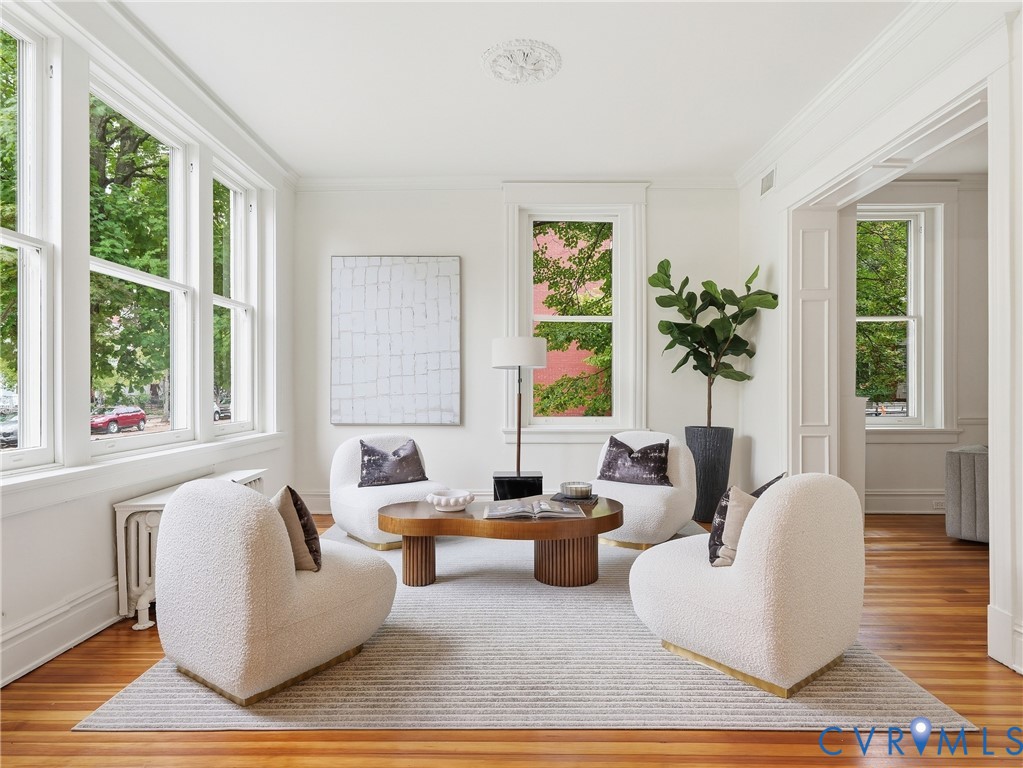 Hardwood flooring throughout, multiple large windows, detailed crown molding, decorative ceiling medallion, and white trim work Hardwood flooring throughout, multiple large windows, detailed crown molding, decorative ceiling medallion, and white trim work