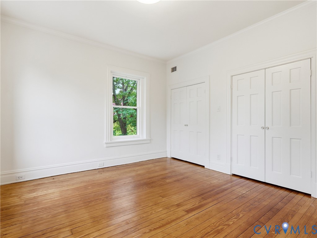 Hardwood flooring, crown molding, double bi-fold closet doors, additional bi-fold closet, and a single window