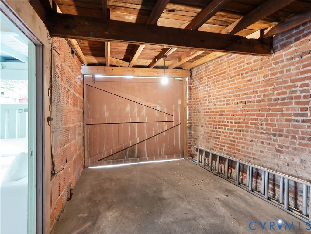 Exposed brick walls, concrete flooring, and an exposed wood beam ceiling