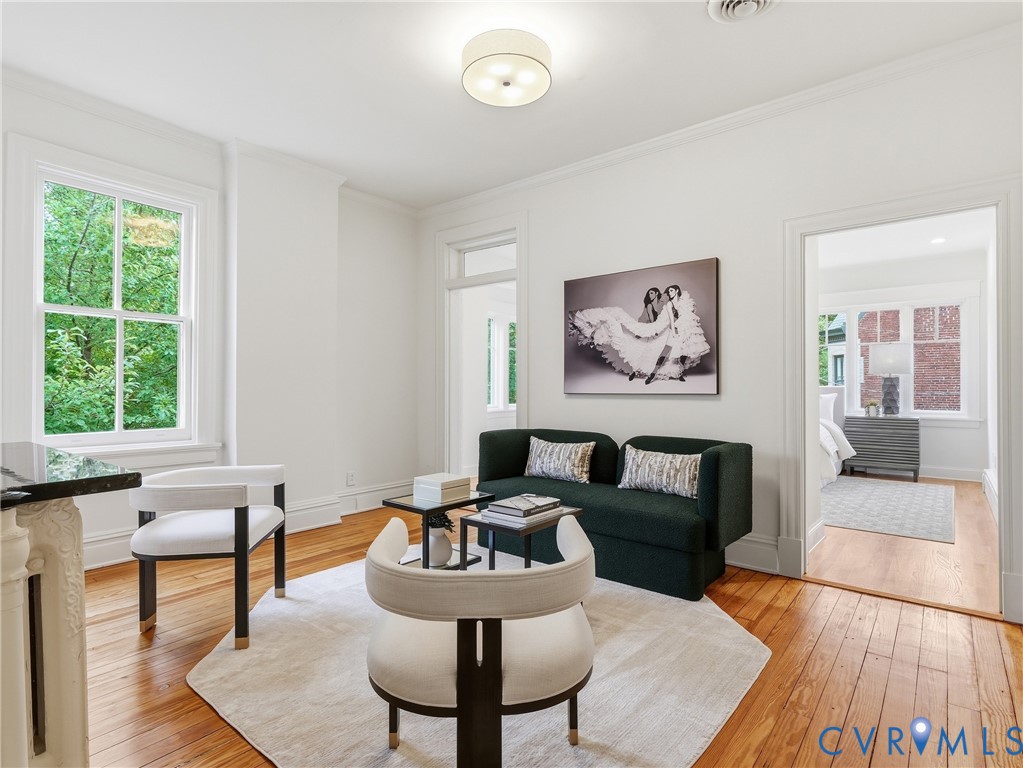 Hardwood flooring throughout, white crown molding, and a built-in overhead light fixture