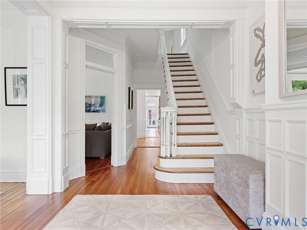Hardwood flooring throughout, white paneled walls, white trim details, and a curved staircase with white risers and wood treads Hardwood flooring throughout, white paneled walls, white trim details, and a curved staircase with white risers and wood treads