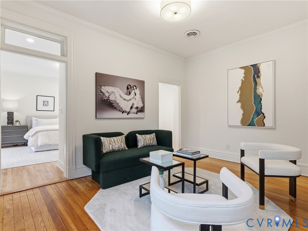 Hardwood flooring, crown molding, cased doorways, and a flush mount ceiling fixture