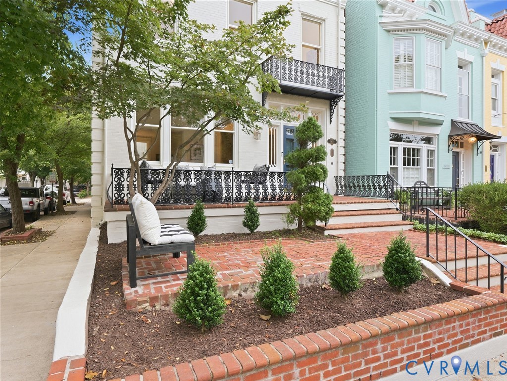 Brick patio with a decorative black iron railing, brick retaining wall, and mature landscaping Brick patio with a decorative black iron railing, brick retaining wall, and mature landscaping
