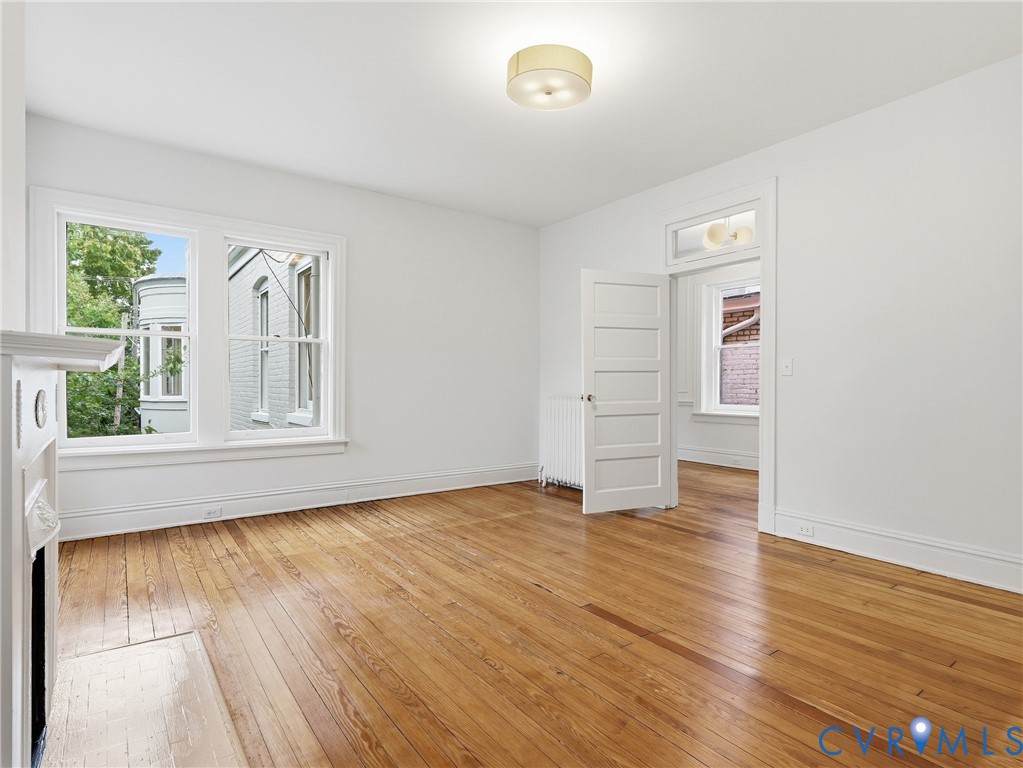 Hardwood flooring, painted white walls, white trim, transom window, and a built-in fireplace