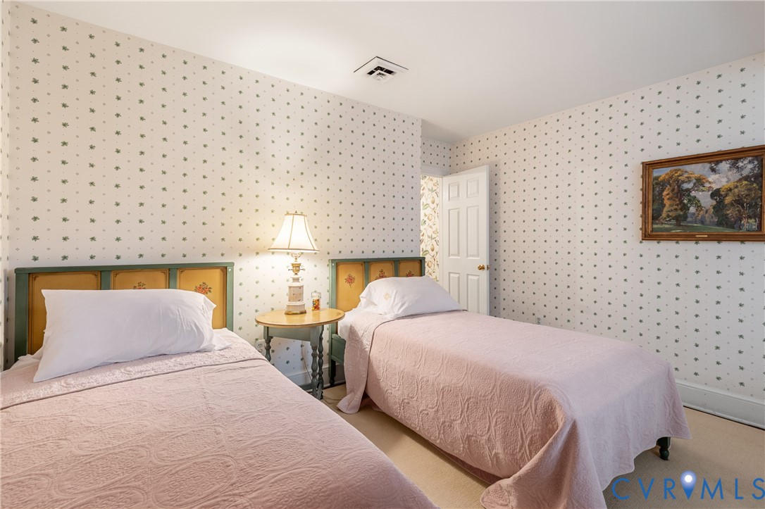 Bedroom featuring patterned wallpaper, carpeted flooring, and a six-panel interior door