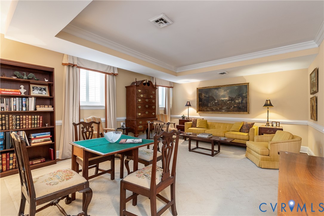 Tray ceiling with crown molding, custom built-in wooden shelving, and wall chair rail trim