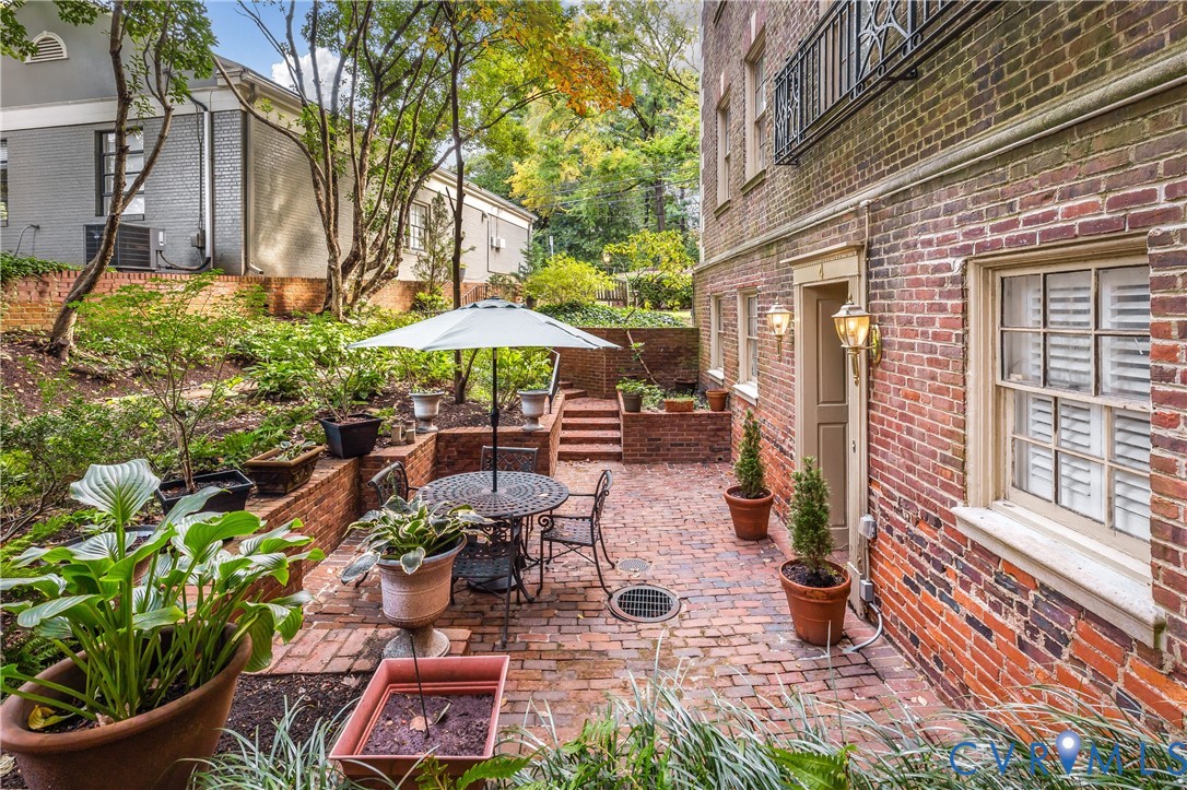 Brick exterior patio featuring multi-level retaining walls, integrated brick steps, and wall-mounted exterior lighting