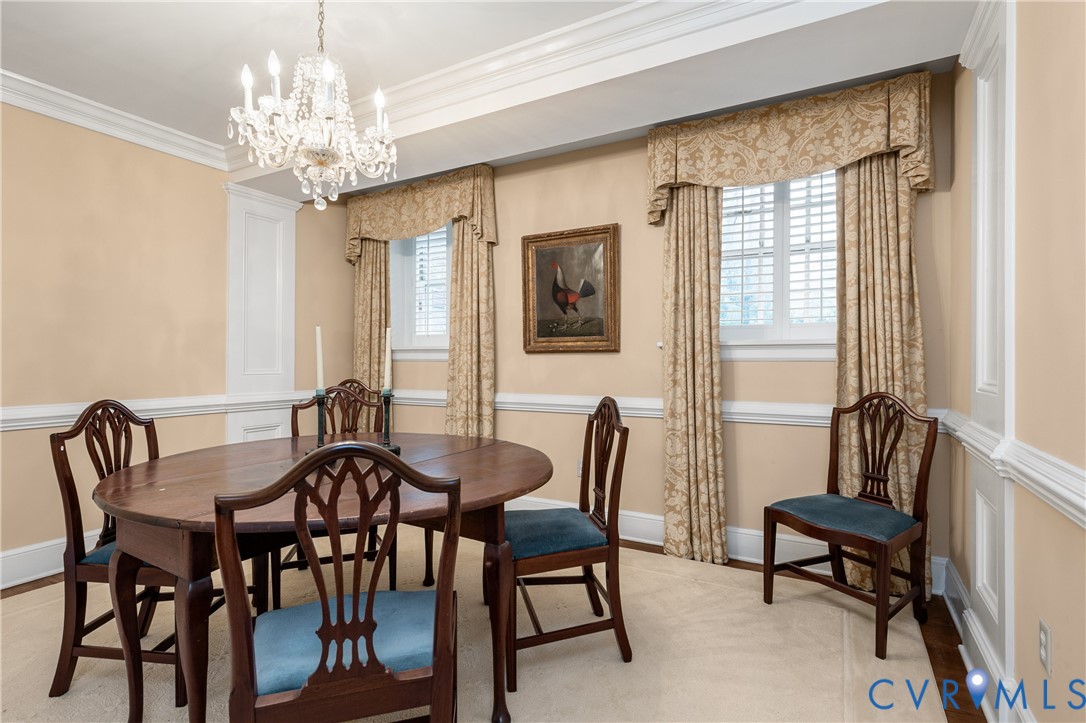 Dining room featuring detailed crown molding, chair rail millwork, and a crystal chandelier
