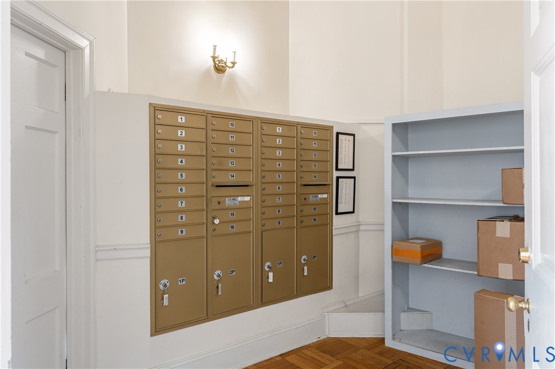 Mailroom area featuring metallic postal lockers, built-in shelving, and wood-finish parquet flooring