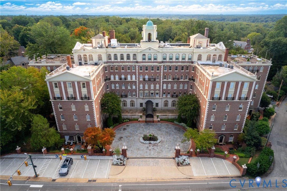 Multi-story brick exterior featuring a central cupola, decorative pilasters, arched windows, and a circular stone-paved motor court