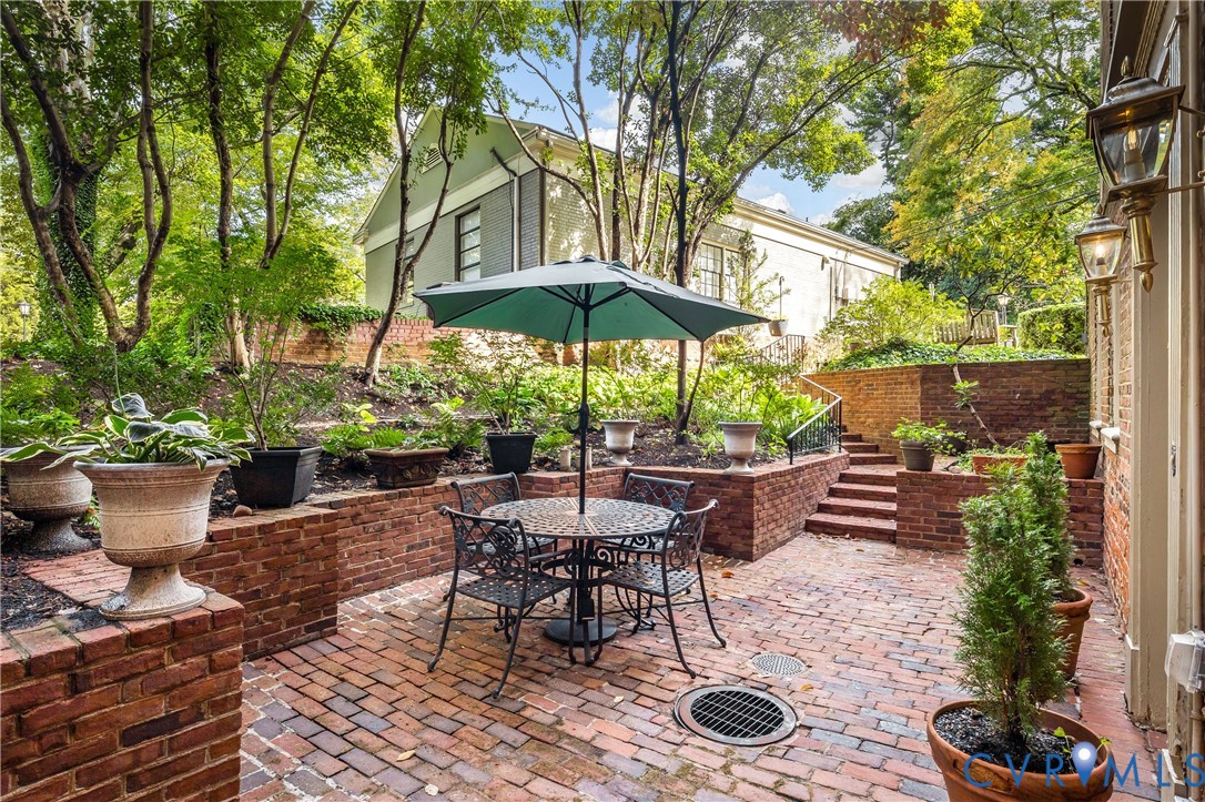 Terraced brick patio featuring multi-level retaining walls, integrated brick staircase, and wall-mounted exterior lanterns