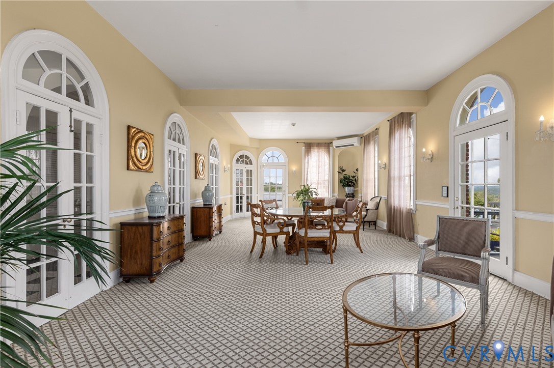 Sunroom featuring arched French doors, patterned carpeting, wall-mounted lighting, and chair rail molding