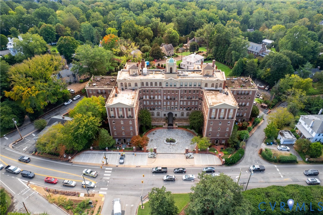 Multi-story brick building with a central cupola, formal stone-paved motor court, and surrounding mature wooded grounds