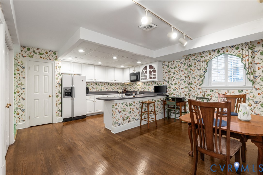 Kitchen featuring white cabinetry, solid-surface countertops, wood-finish flooring, an arched window, and track lighting