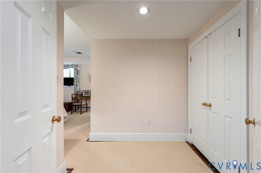 Neutral-toned wallpaper, recessed ceiling lighting, and double-door closet with brass-finish hardware