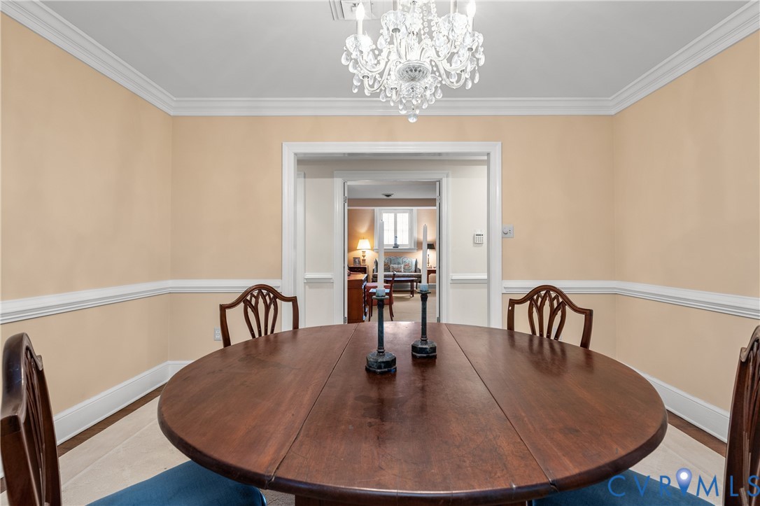 Dining space featuring a multi-tiered crystal chandelier, crown molding, and chair rail wainscoting