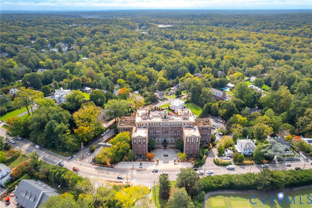 Multi-story masonry exterior featuring a central cupola, formal circular motor court, expansive grounds, and abundant surrounding mature canopy