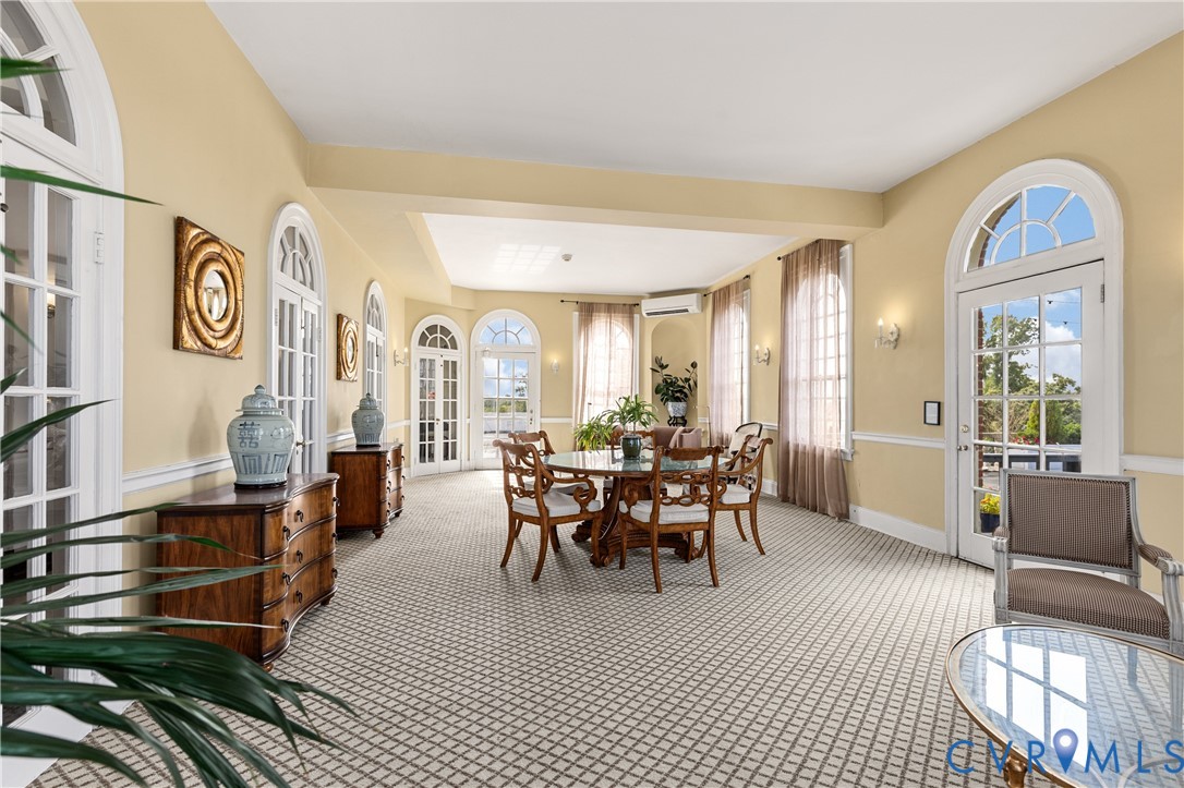Expansive room featuring multiple arched glass-paned entry doors, chair rail molding, and high-reaching ceilings