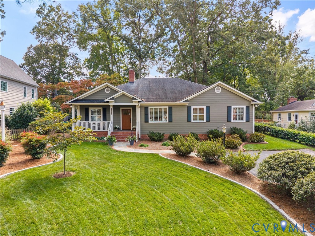 Siding exterior with decorative shutters, covered front porch, and a brick chimney
