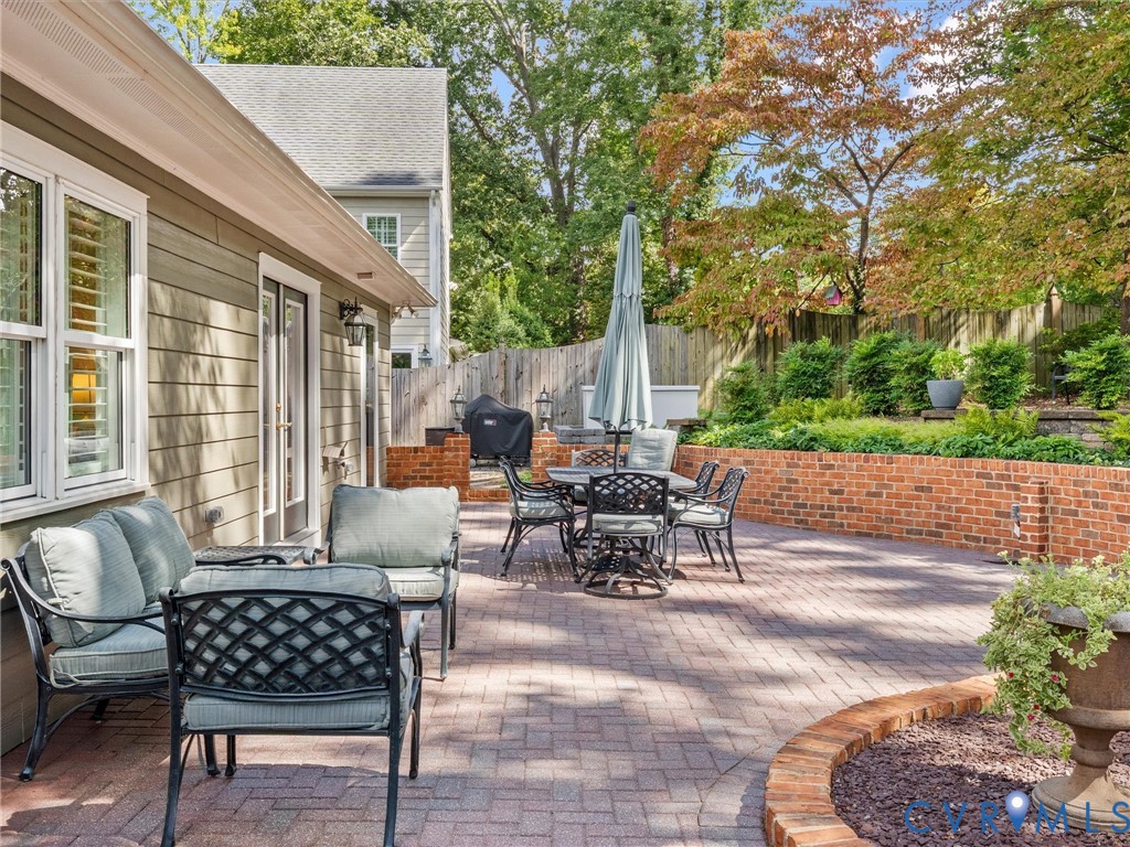 Expansive brick paver patio featuring a raised brick planter and surrounding mature trees