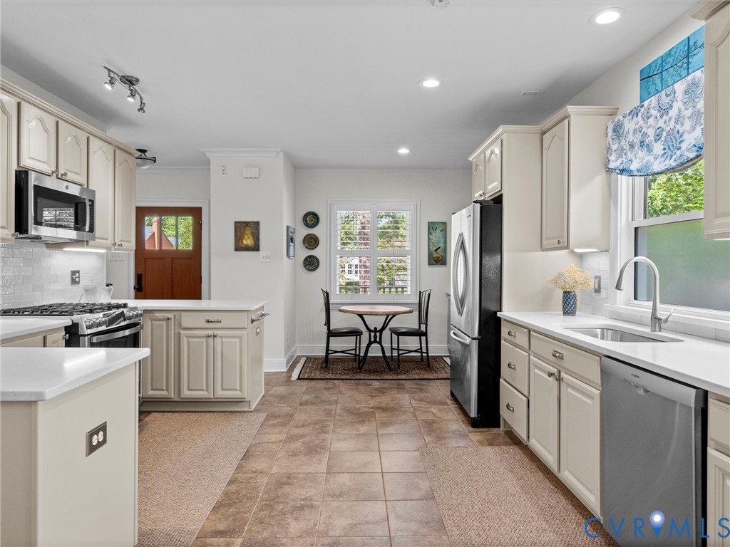 White shaker-style cabinetry with chrome hardware, stainless steel appliances, white countertops, tile backsplash, and recessed lighting