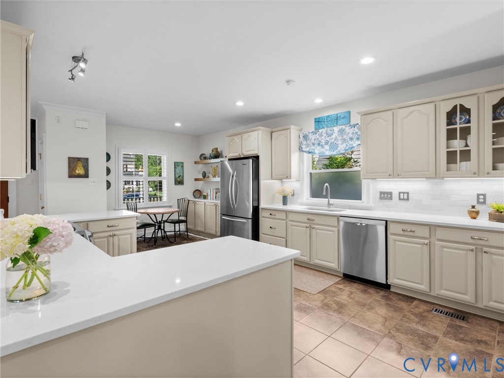 Kitchen with light-toned cabinetry, stainless steel appliances, white countertops, and tiled flooring