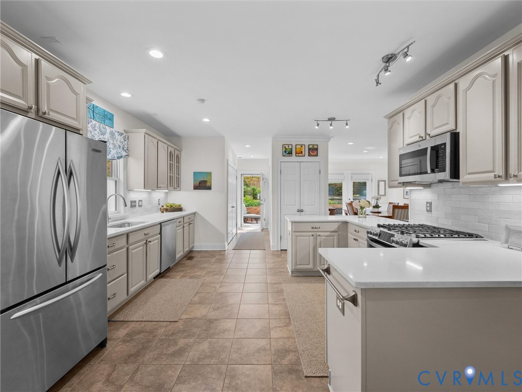 Kitchen featuring stainless steel appliances, light cabinetry, white countertops, tile flooring, and recessed lighting