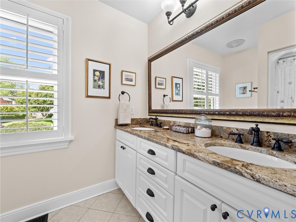 Dual vanity with granite countertop, white cabinetry, and matte black fixtures