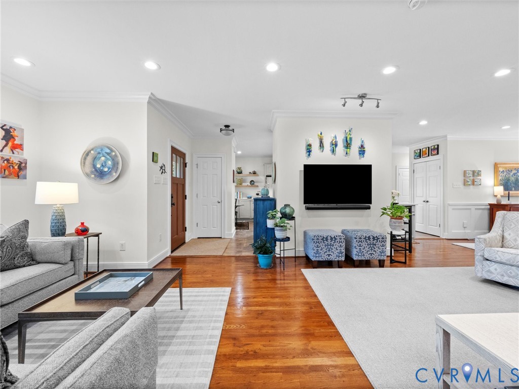 Recessed lighting illuminates the living space with wood-finish flooring