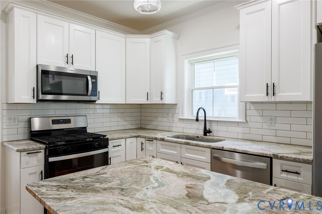 Kitchen featuring white cabinetry, stone countertops, a subway tile backsplash, stainless steel appliances, and a matte black gooseneck faucet
