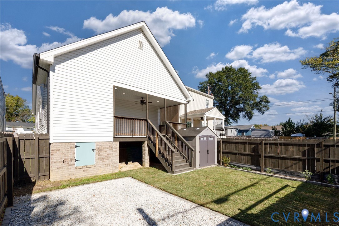 Vinyl siding exterior featuring a covered porch, wood-style staircase with railings, gravel patio area, and enclosed backyard with wood fencing
