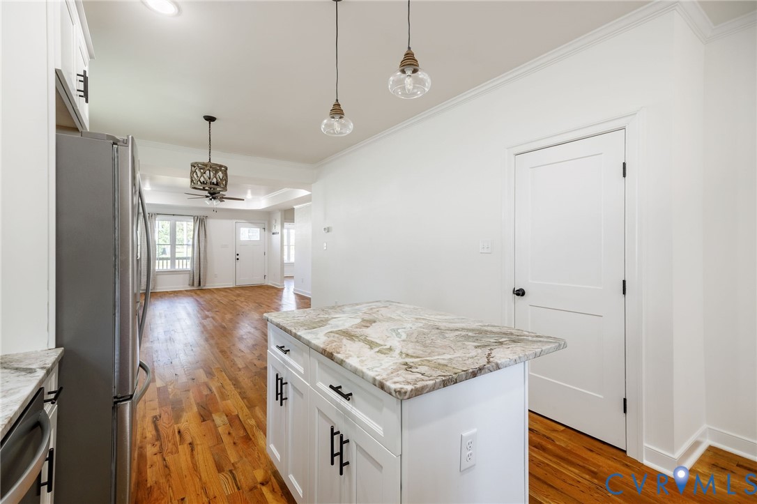Kitchen featuring white cabinetry, stone-surface countertops, wood-finish flooring, dual glass pendant lighting, and stainless steel appliances