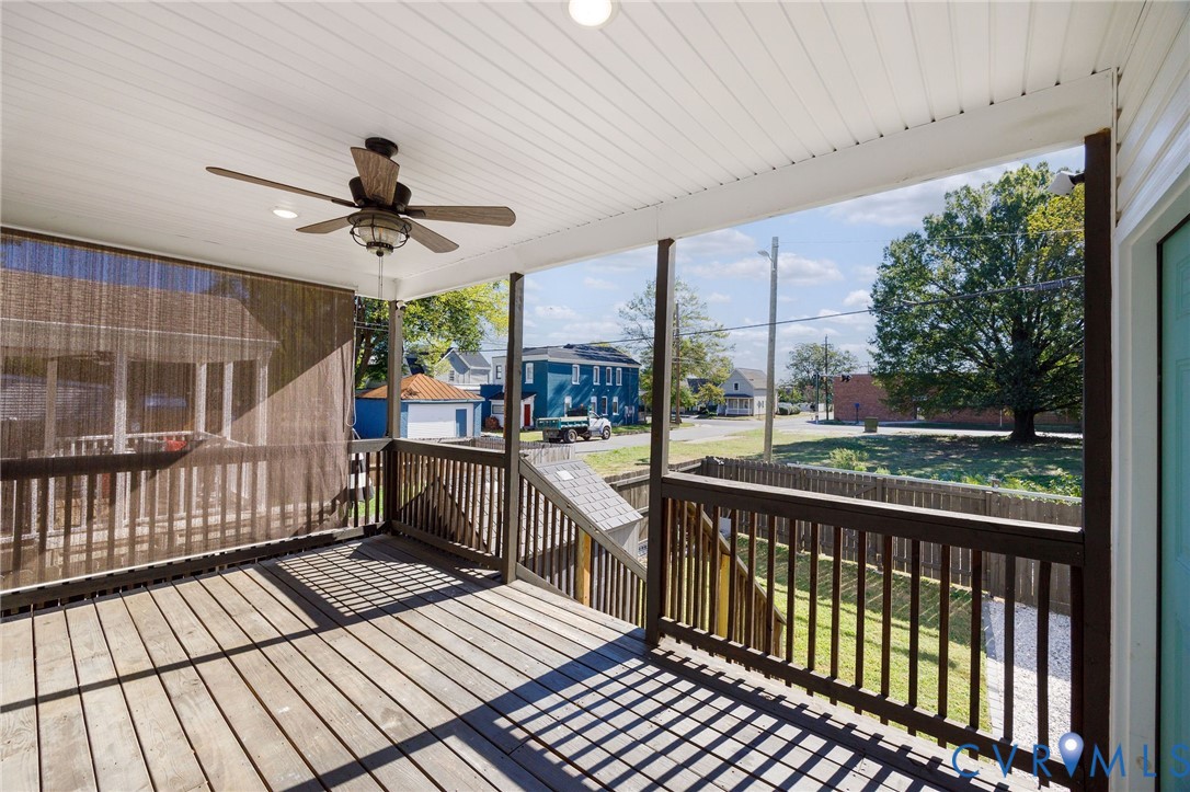 Covered deck featuring wood-finish flooring, a ceiling fan, and dark-stained wood railings