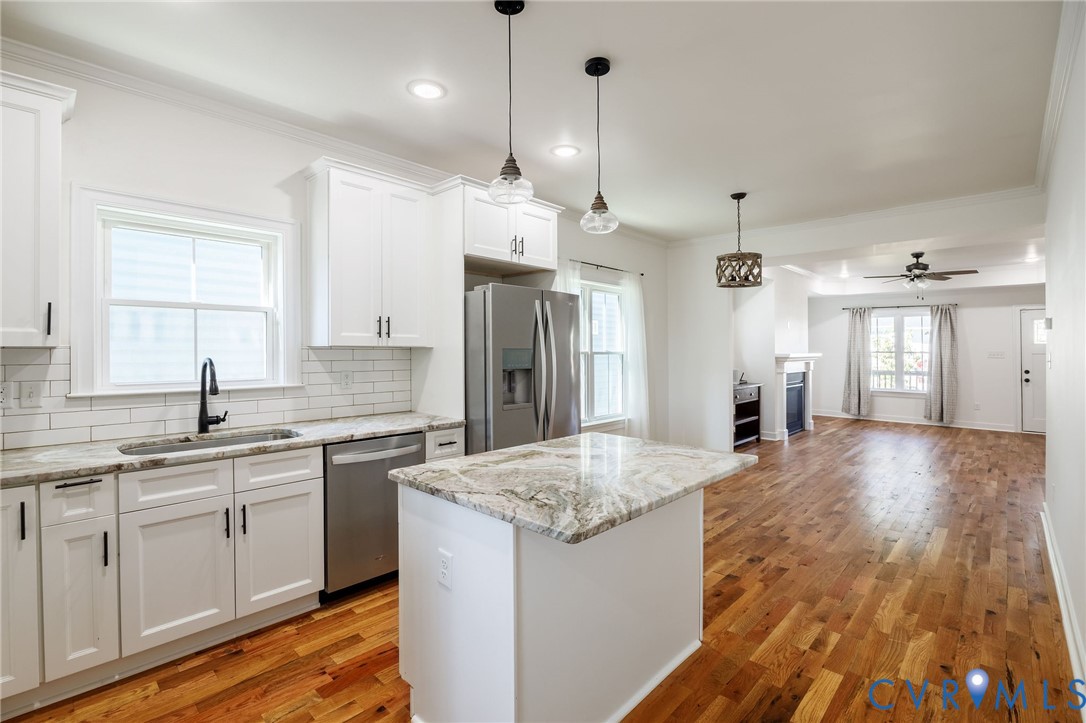 Kitchen featuring white shaker cabinetry, stone-surface countertops, subway tile backsplash, center island, and wood-finish flooring
