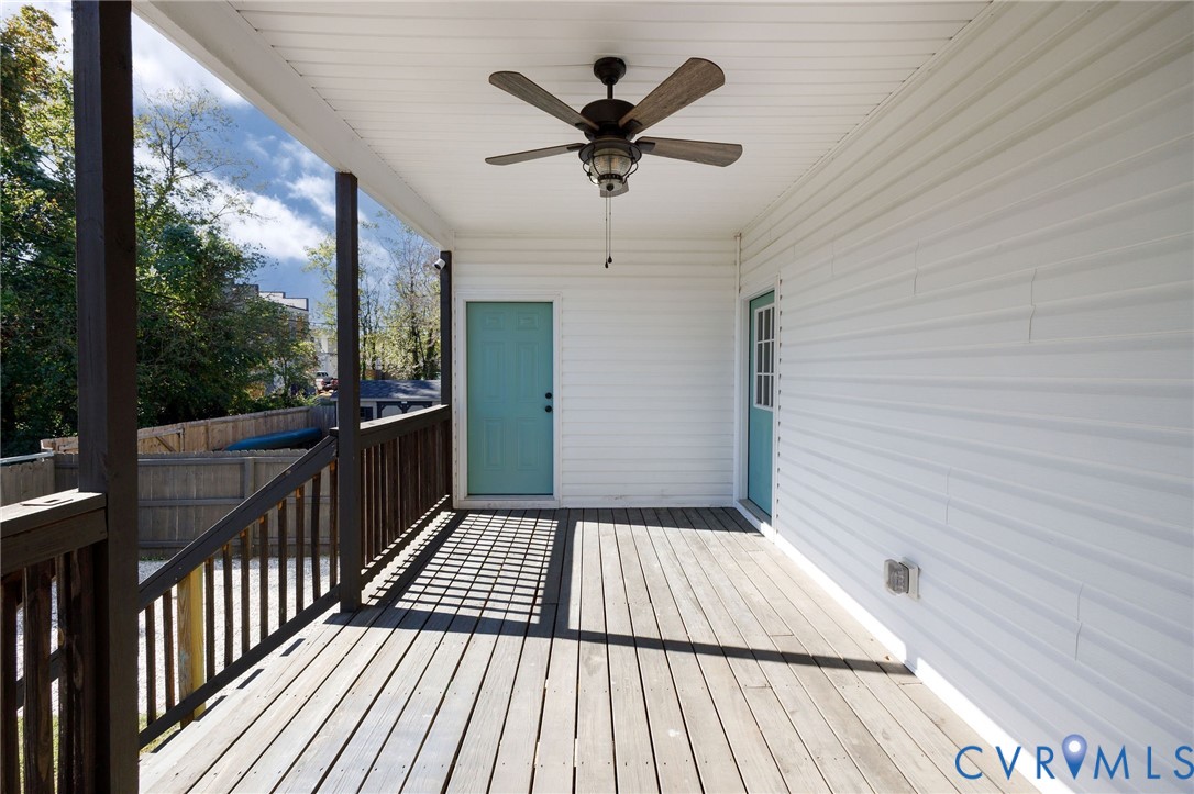 Covered deck featuring wood-finish flooring, a ceiling fan, and two exterior doors with wood-finish railing