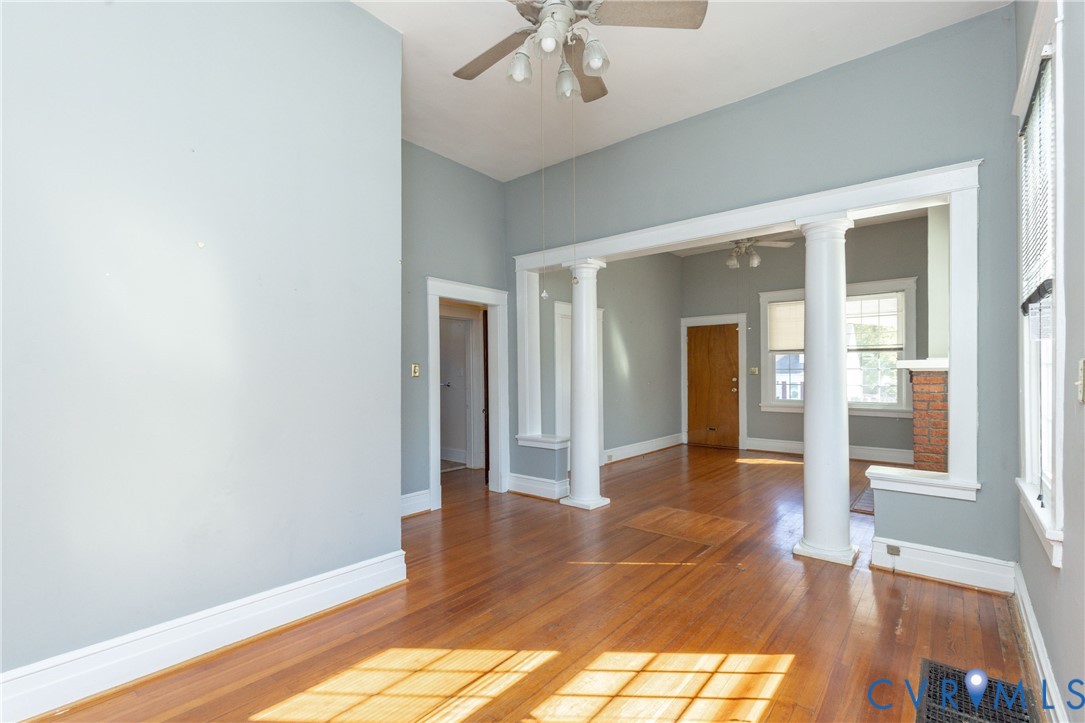 Interior featuring high ceilings, wood-finish flooring, white structural columns, and multi-pane windows