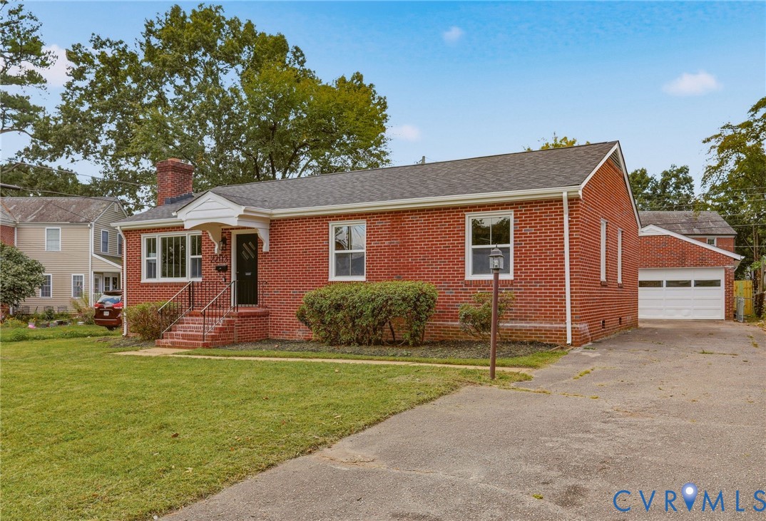 Brick exterior construction featuring a covered front entry, asphalt shingle roof, and attached garage with a white overhead door