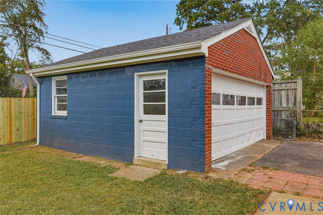 Detached garage featuring brick and painted block exterior, white overhead door with upper window panels, and a side access door