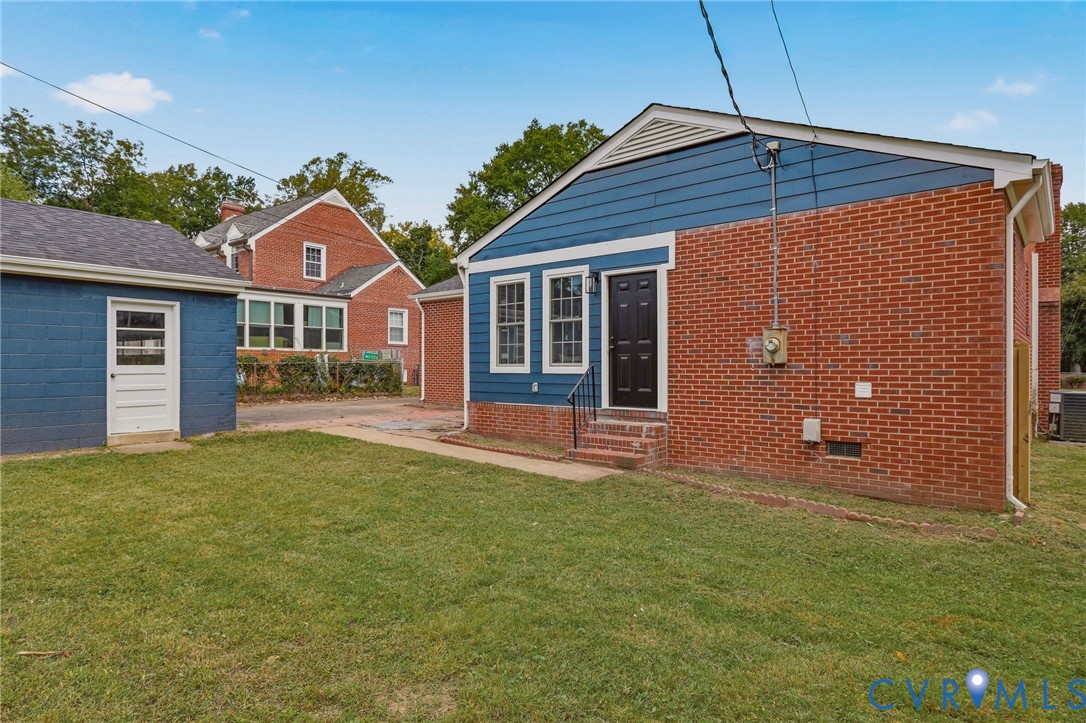 Brick and siding exterior with a dark-paneled entry door, adjacent to a detached structure with a white entry door
