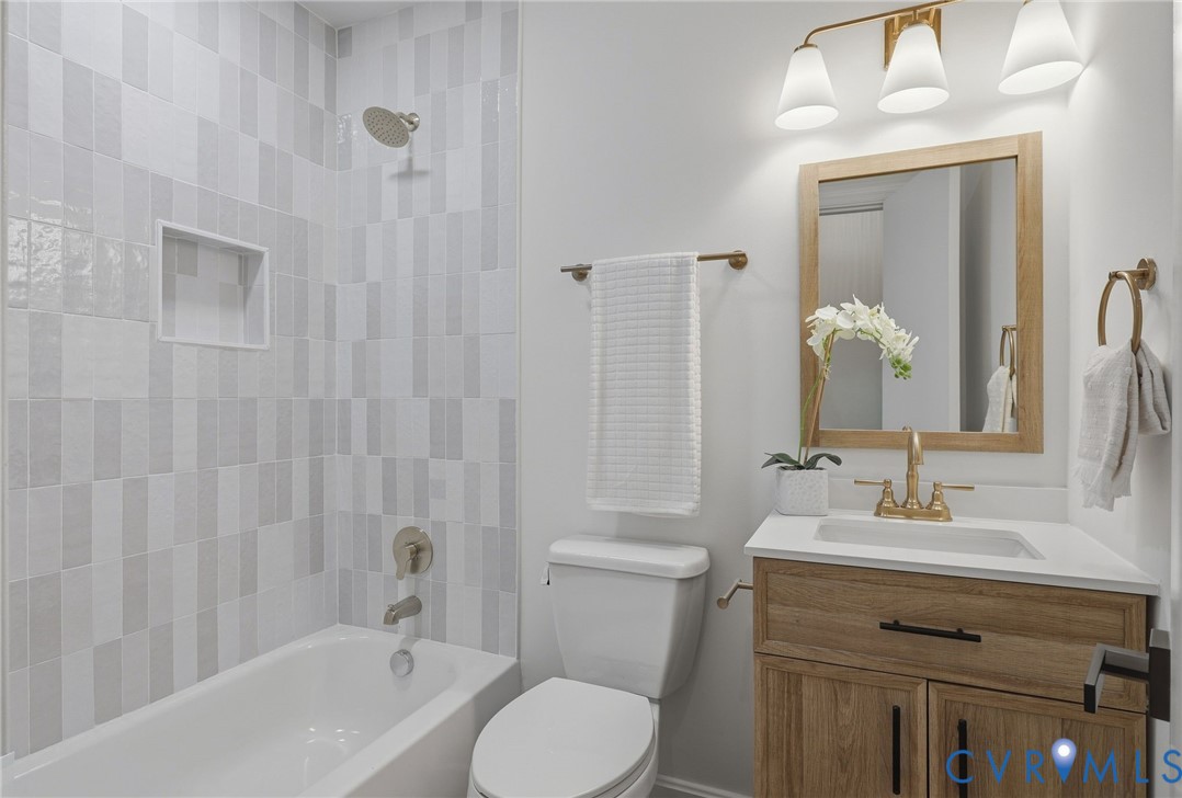 Bathtub with tiled surround, integrated shower niche, and brushed nickel fixtures